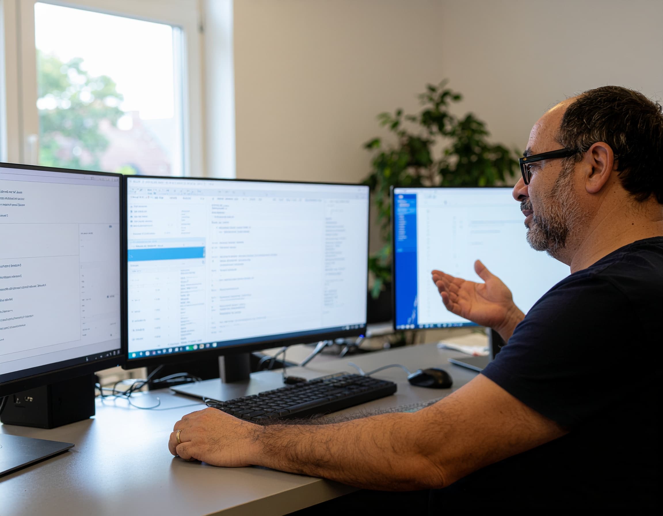 A claims specialist working across three monitors